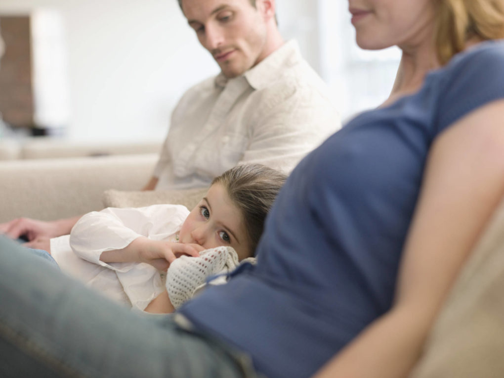 Girl Resting on Sofa Between Parents