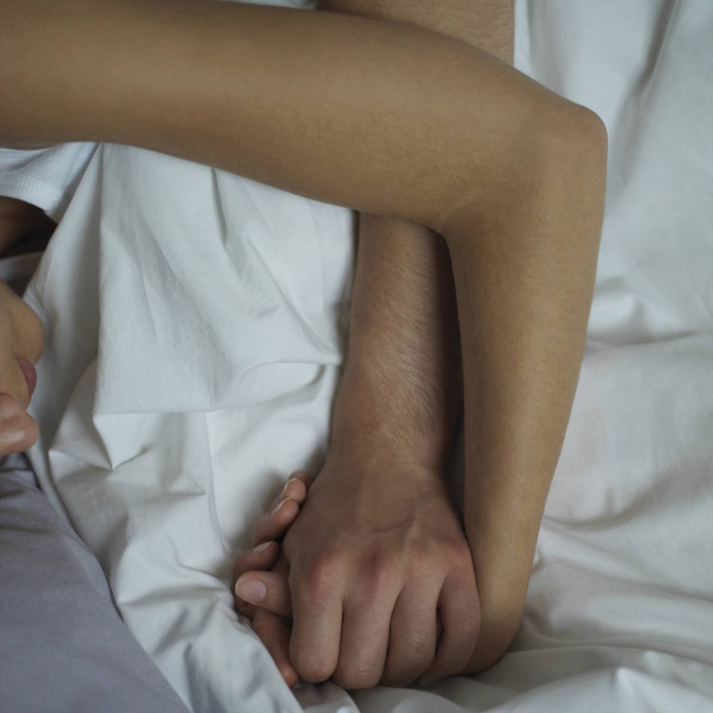 couple holding hands in bed