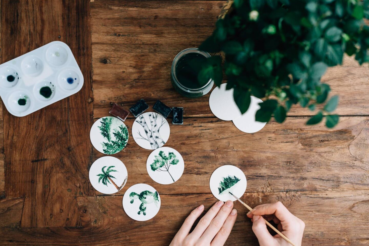 woman painting botanicals on white discs