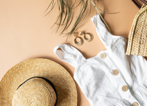 straw summer hat, white linen summer dress, gold earrings and a palm frond flatlay