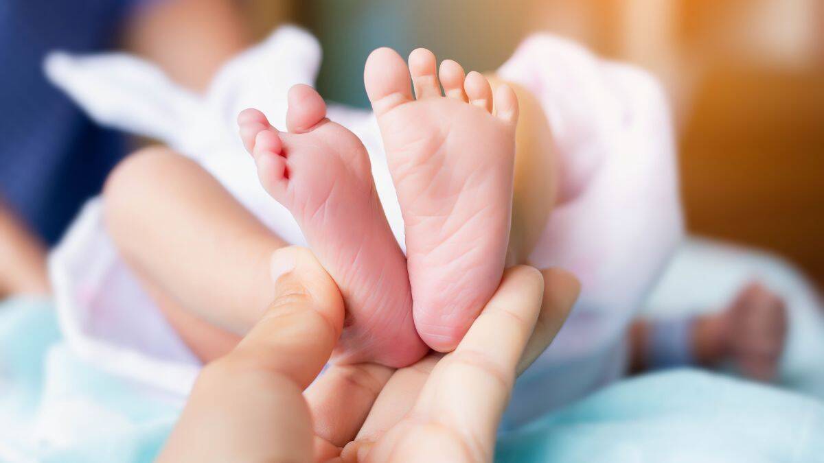 newborn baby's feet as seen from the soles with a midwife's hand supporting the heels