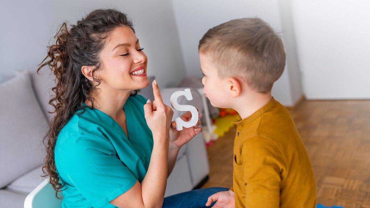 speech therapist and child with a block letter S